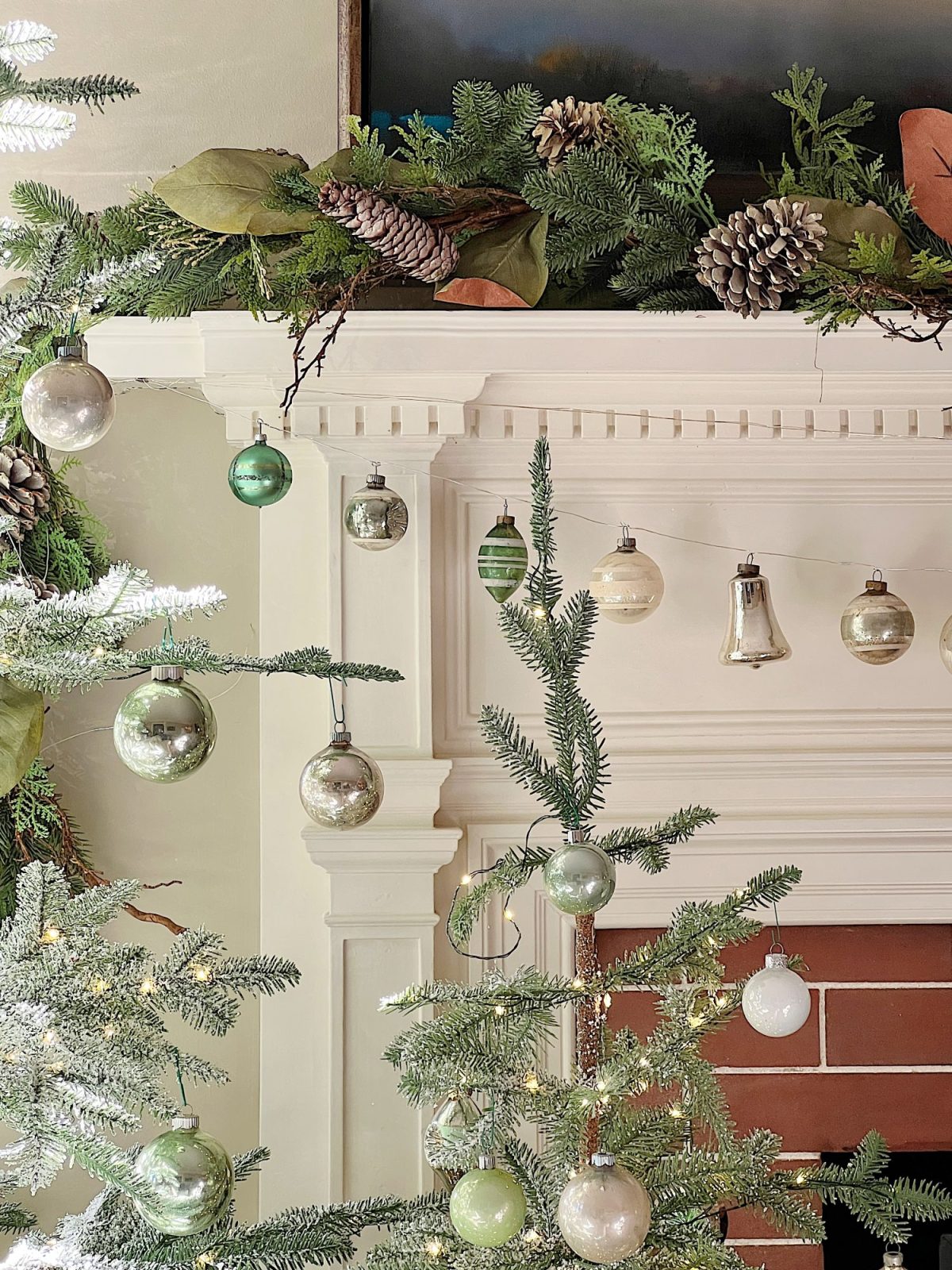 A living room decorated in neutral colors of tan, white, silver, and light green with silver frosted trees, white poinsettias and more holiday decor.