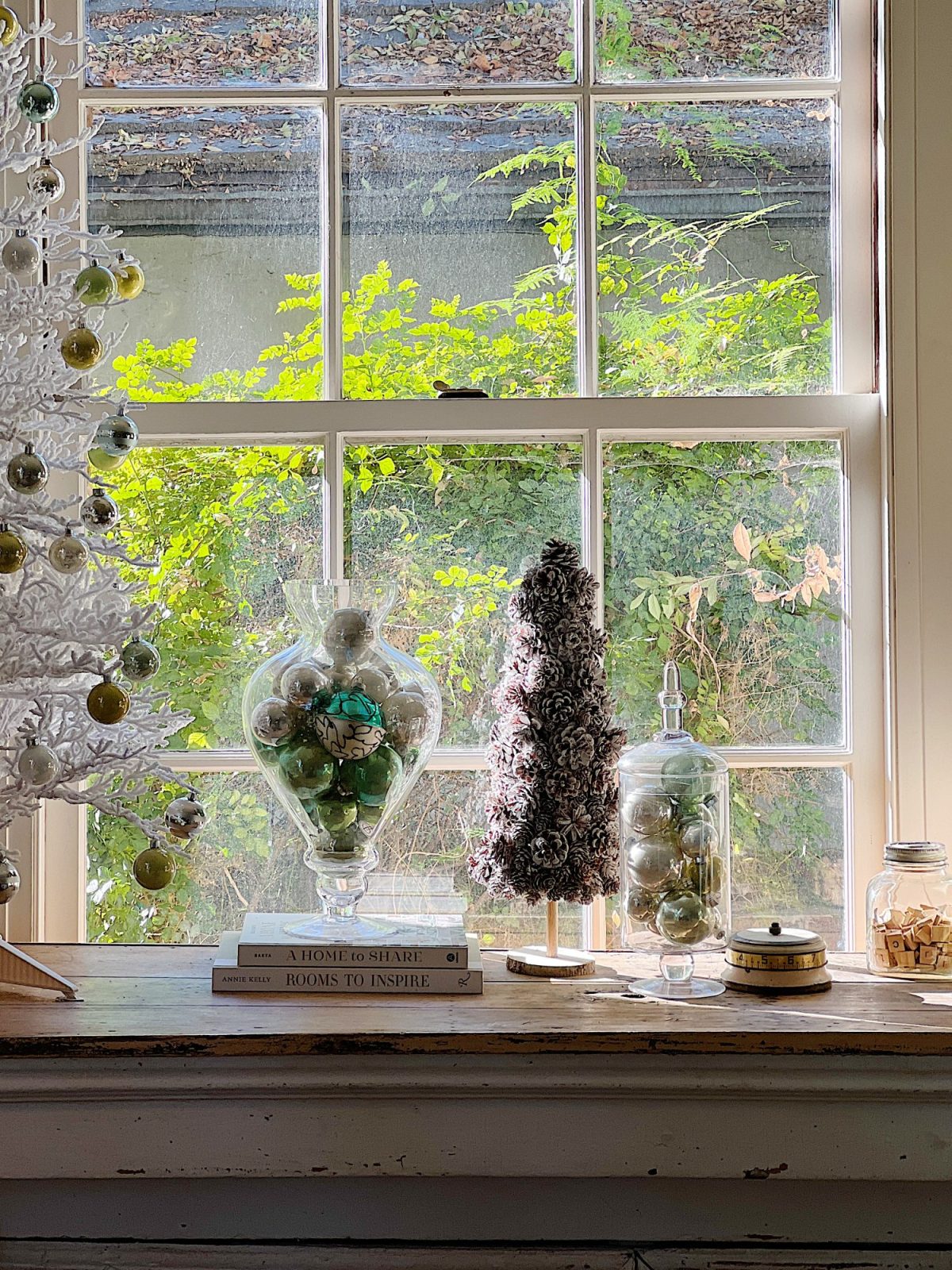A living room decorated in neutral colors of tan, white, silver, and light green with silver frosted trees, white poinsettias and more holiday decor.