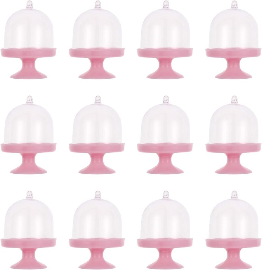 Twelve pink cupcake stands with clear domes, reminiscent of a Valentine's Day charcuterie board, are elegantly arranged in a grid pattern.