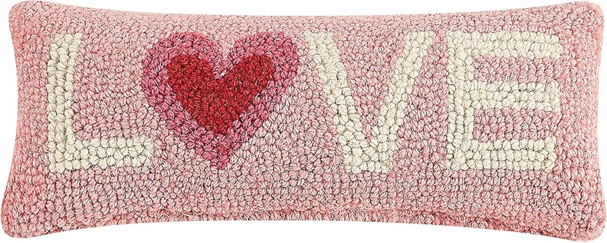 A rectangular pink heart pillow displays the word "LOVE" in white letters, with a red heart cleverly replacing the letter "O.