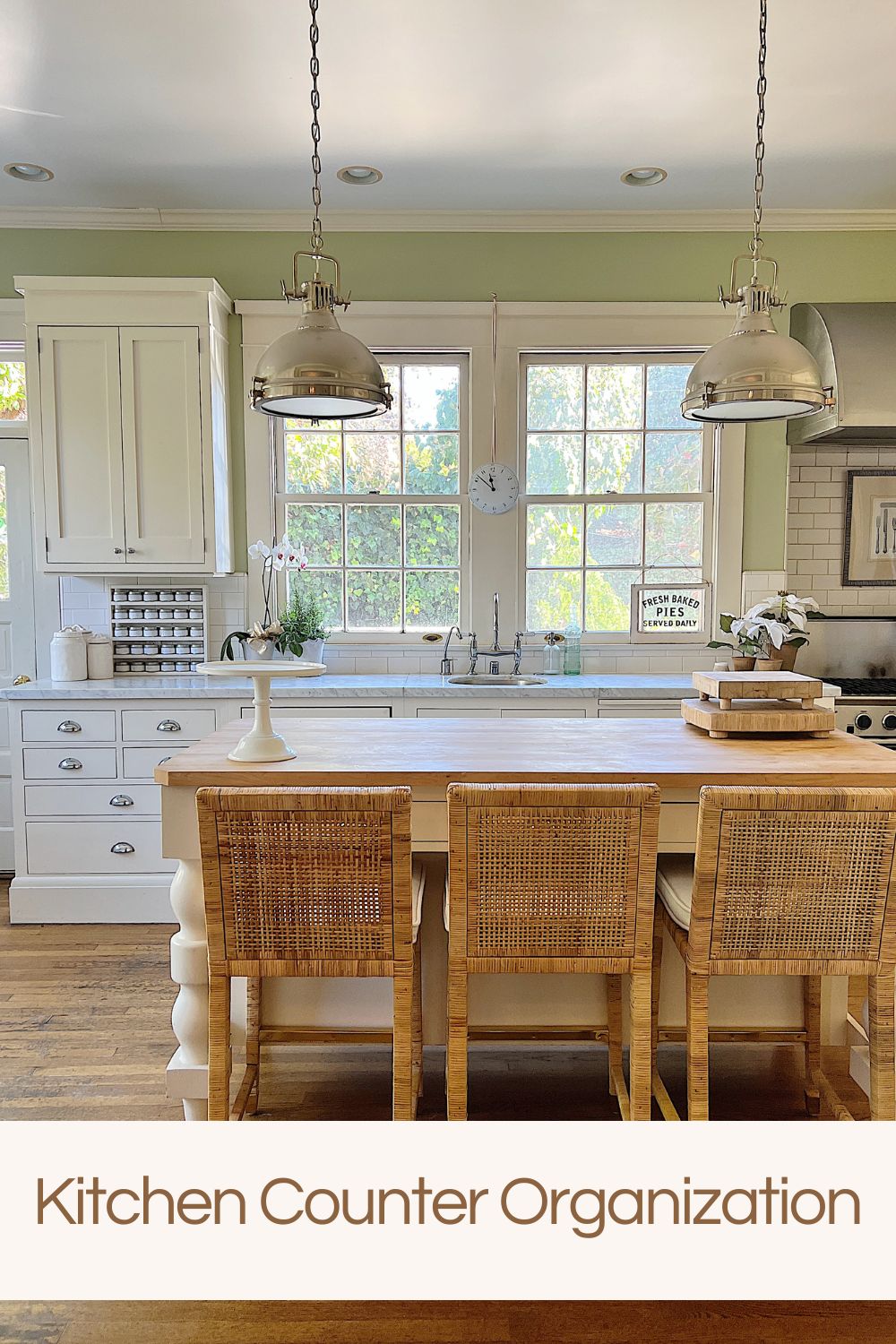 Our kitchen with new counter stools at the island, light green walls, white cabinets, and marble counter tops.