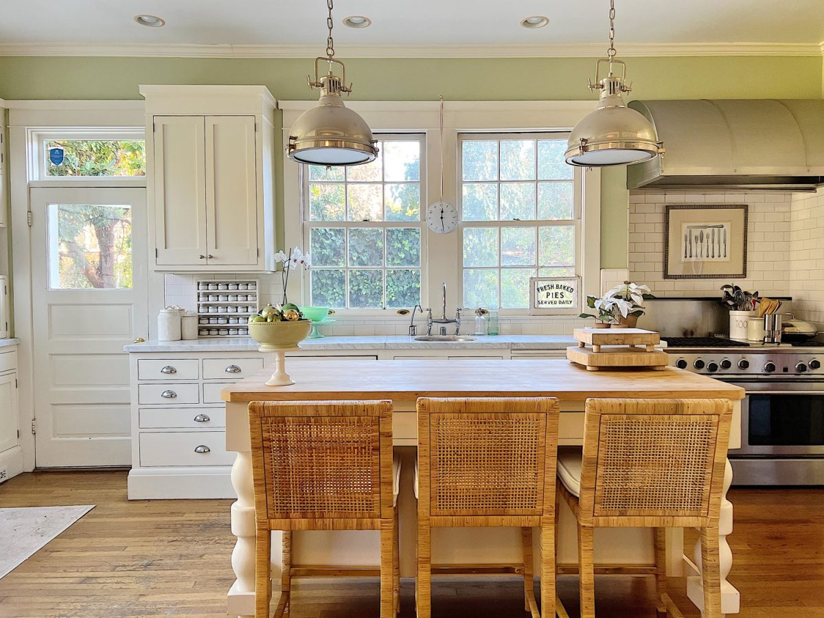 Our kitchen with new counter stools at the island, light green walls, white cabinets, and marble counter tops.