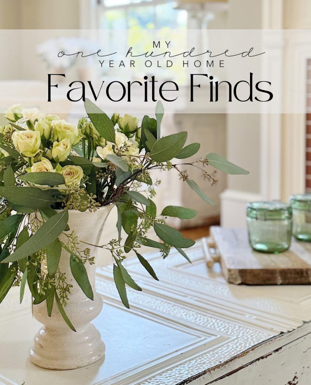 A coffee table in a white living room with a vase filled with roses and eucalyptus.