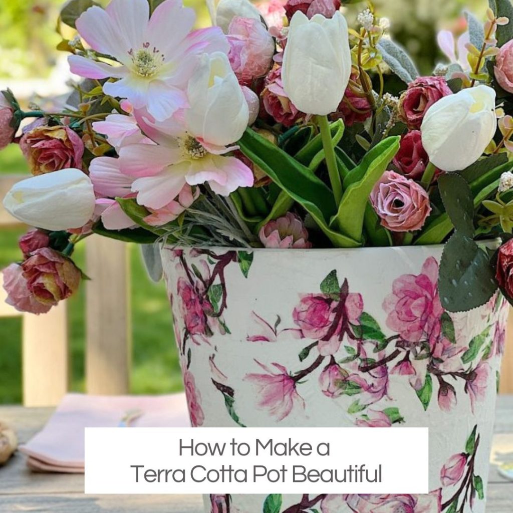 A terracotta pot covered with a flowered napkin with faux pink and white flowers.