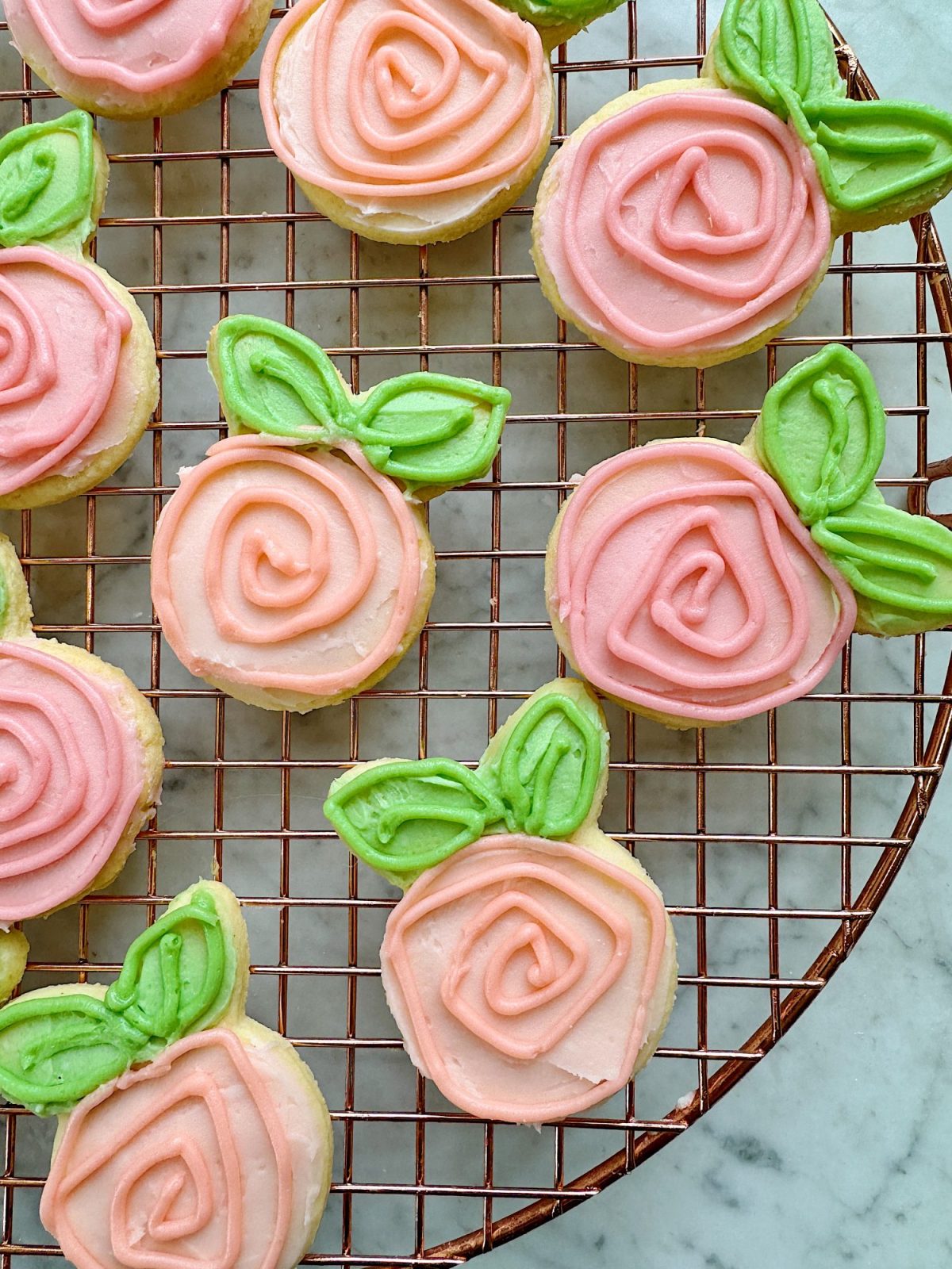 Flower shaped cookies decorated with bright colored buttercream frosting.