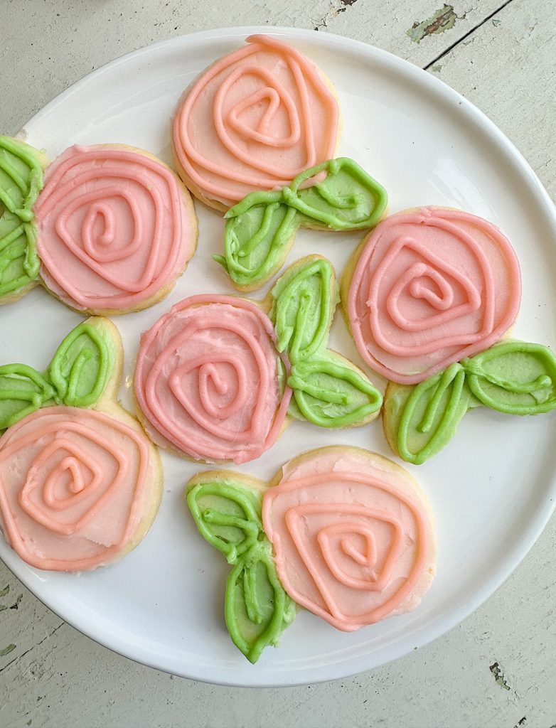 Flower shaped cookies decorated with bright colored buttercream frosting.
