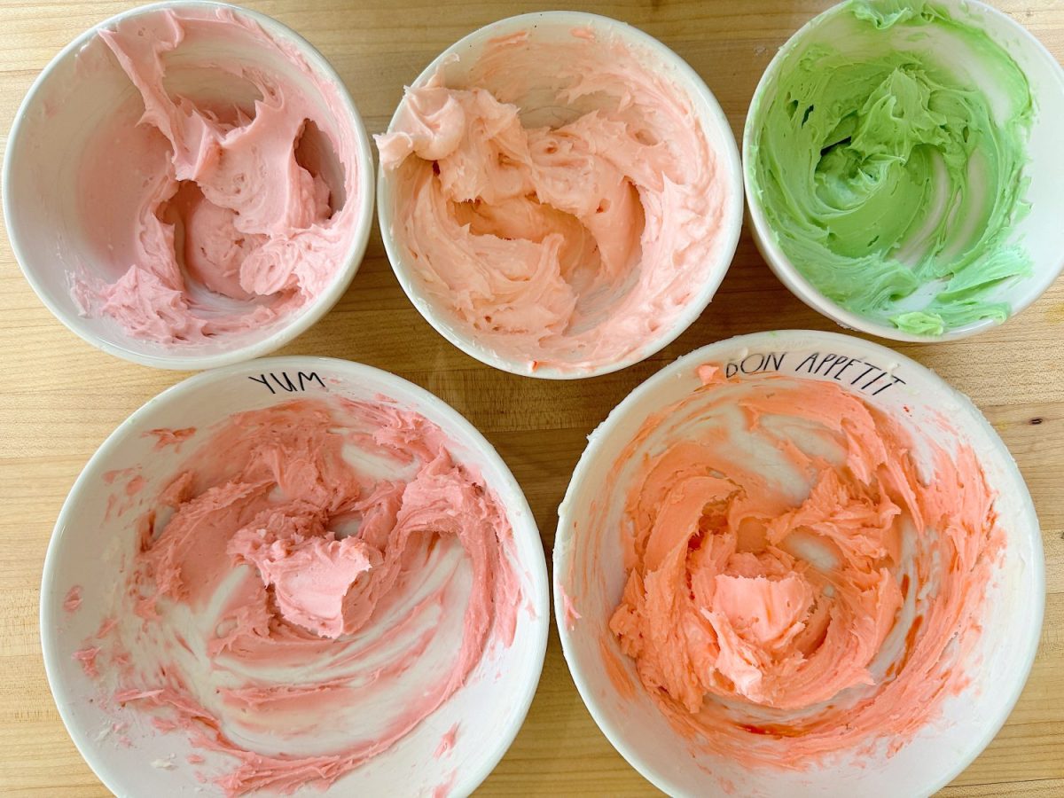 Flower shaped cookies decorated with bright colored buttercream frosting.
