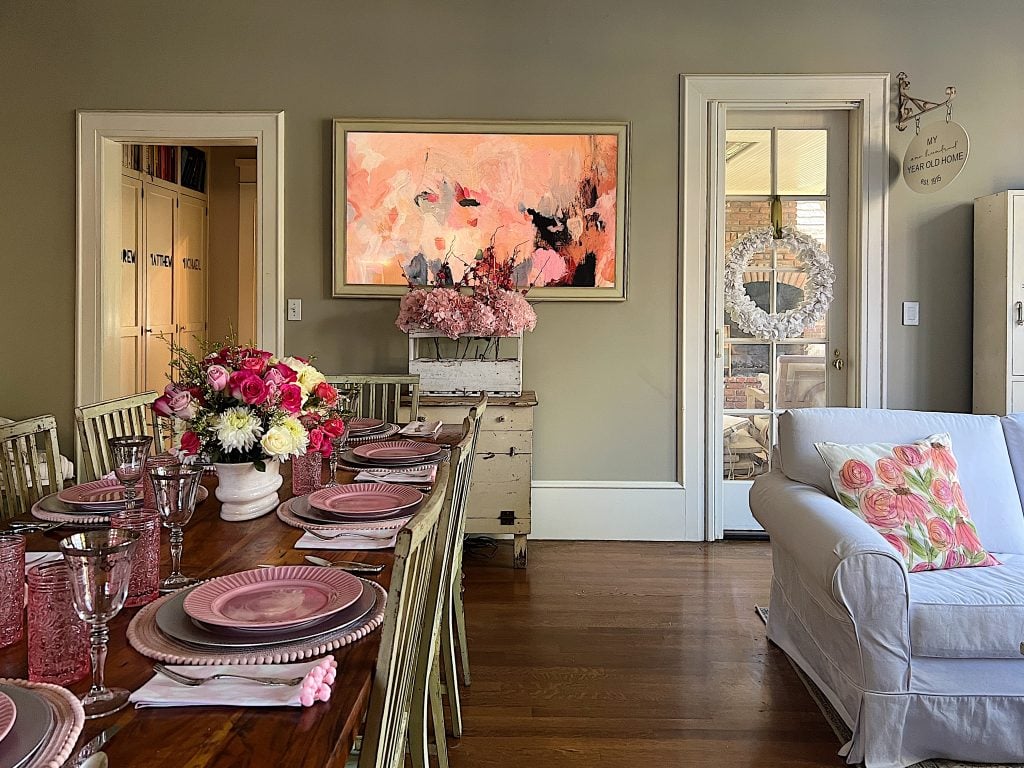 Our family room dining table set for a pink themed Valentine's Day dinner and the Frame TV with a pink and peach modern art design.