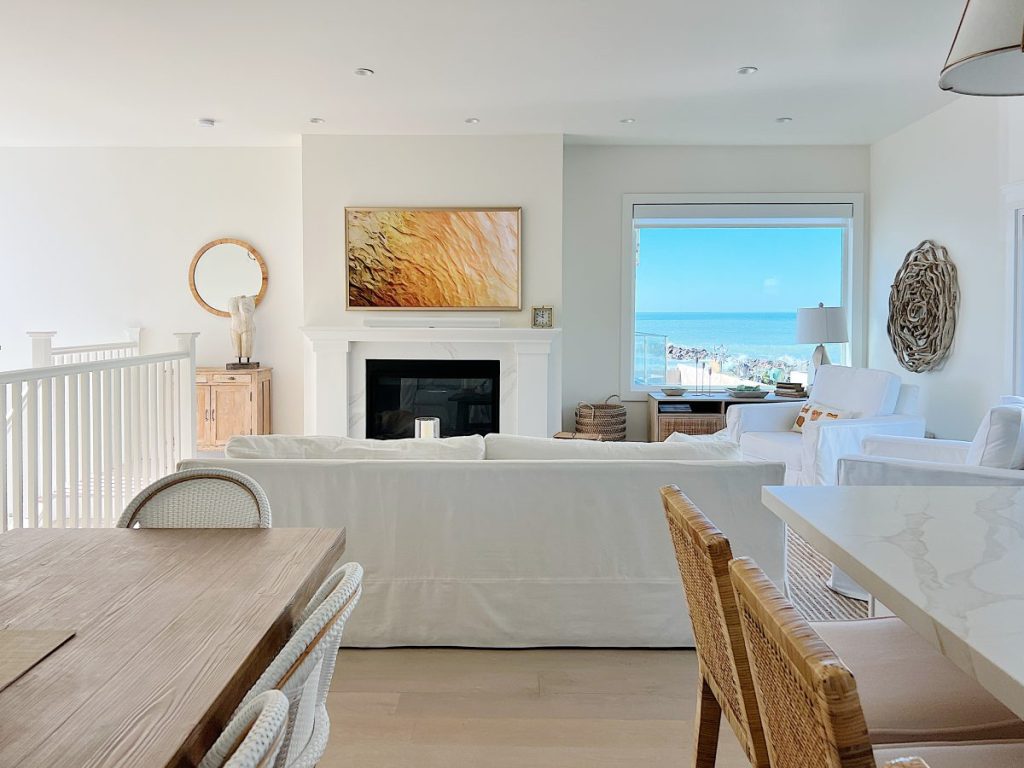 Our Ventura Beach house with art on the Frame TV, an ocean view, and white and tan furniture.