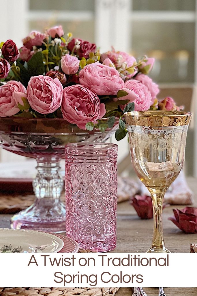 A floral arrangement of pink peonies in a vase on a table, accompanied by ornate glassware, with text overlay "a twist on traditional spring colors".