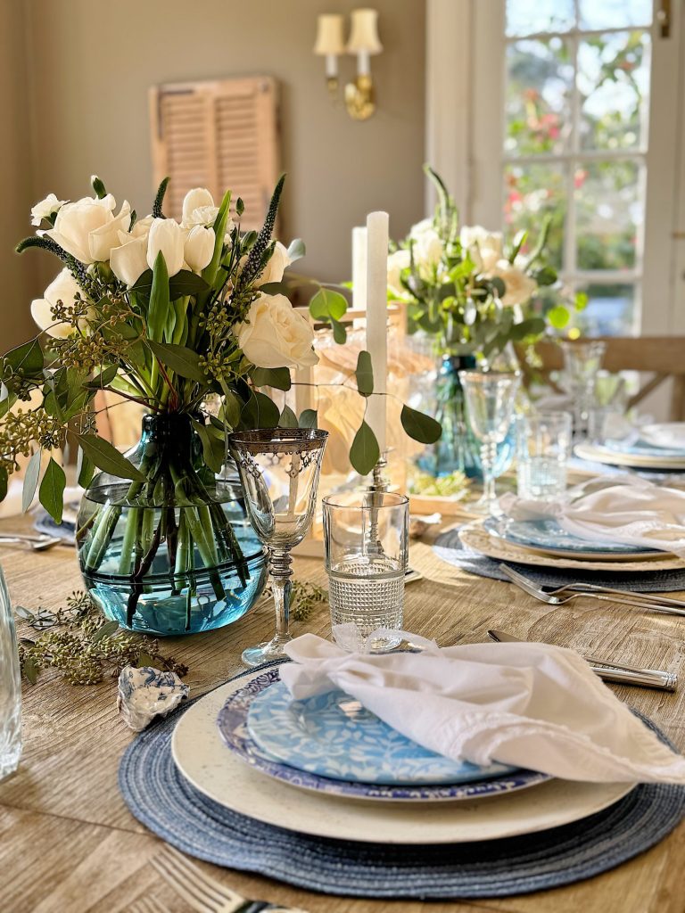 Elegant table setting with floral centerpiece and fine dinnerware in a warmly lit room.