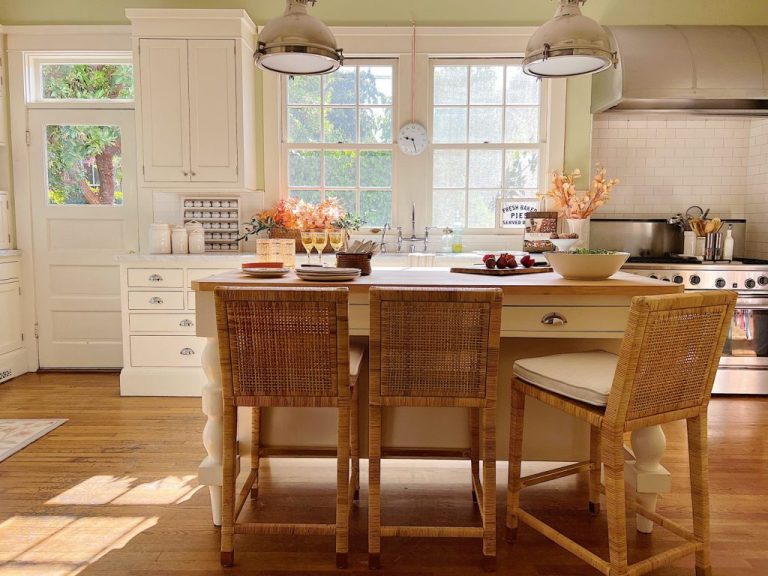 Our kitchen island in our white kitchen with three rattan counter stools.