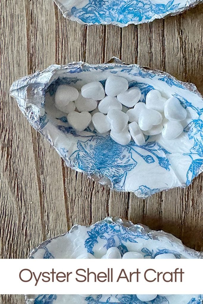 Oyster shells decorated with blue napkin patterns and filled with small white candies.