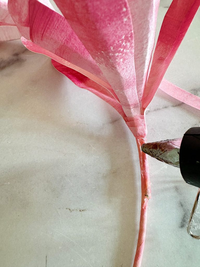 Pink floral tape partially wrapped around a stem resting on a marble surface.
