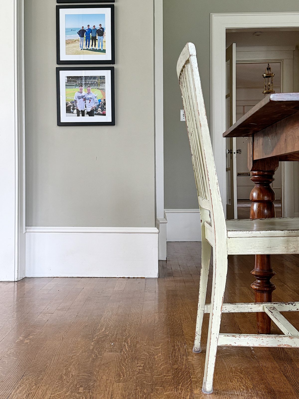 A wooden chair beside a table, facing a wall with framed photographs.
