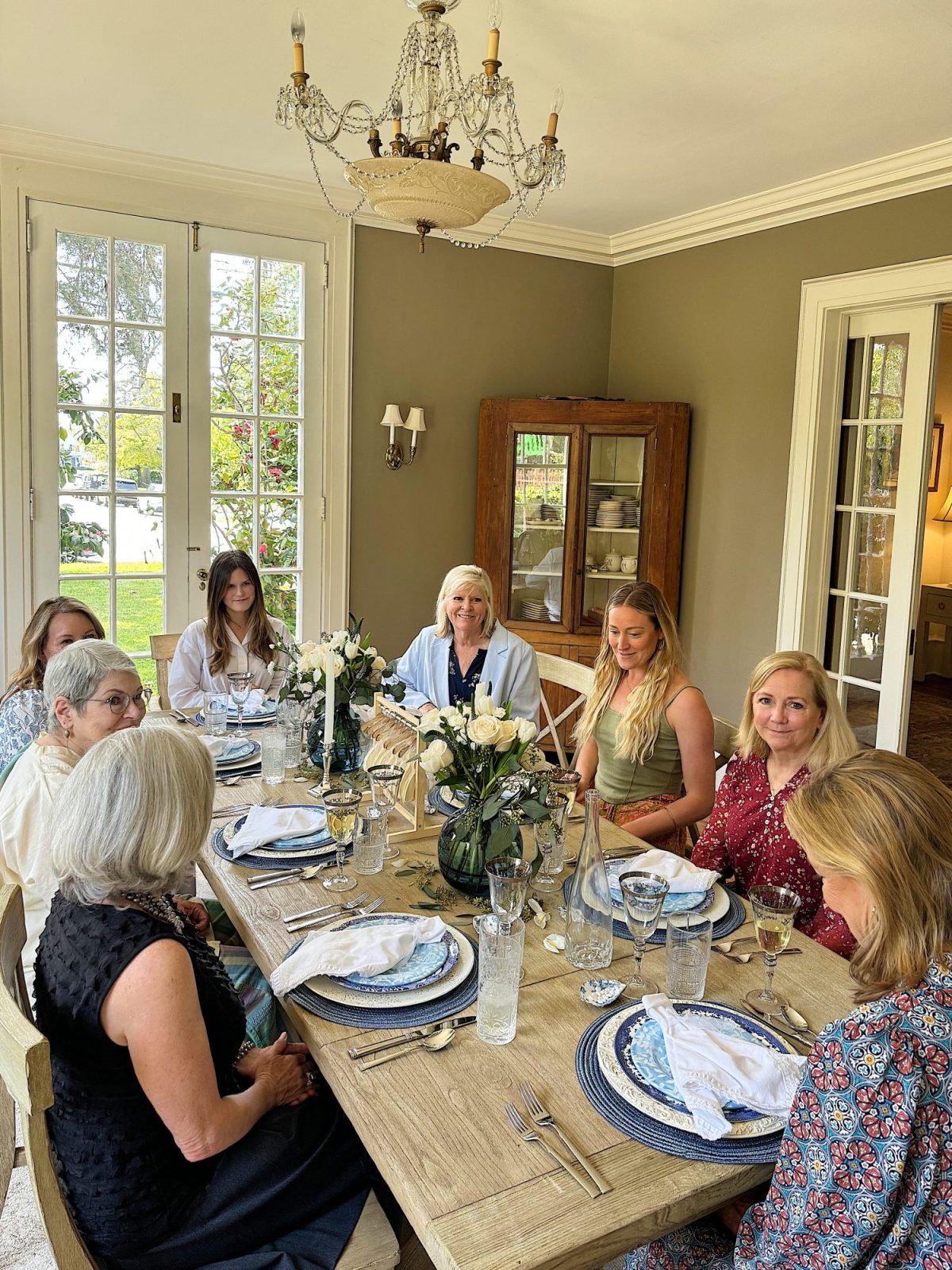 A group of people enjoying a meal together around a dining table in a well-lit room.