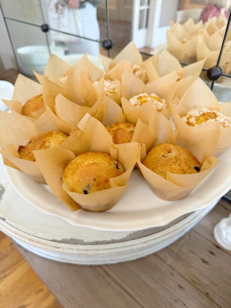 A plate of freshly baked muffins presented in parchment paper liners on a table.