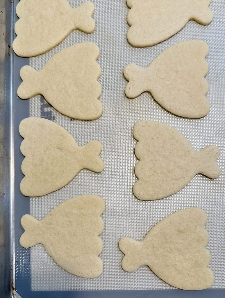 Unbaked dress-shaped cookies on a baking sheet.