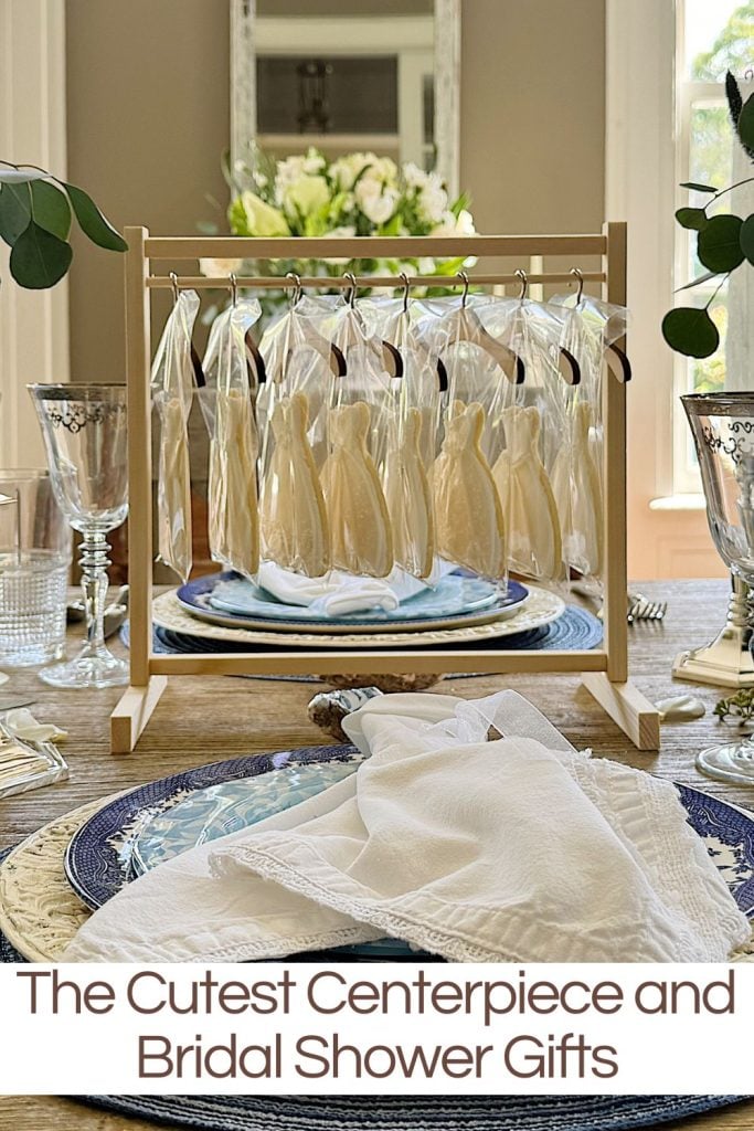 Elegant table setting with a unique centerpiece featuring hanging miniature dresses and bridal shower gift ideas.