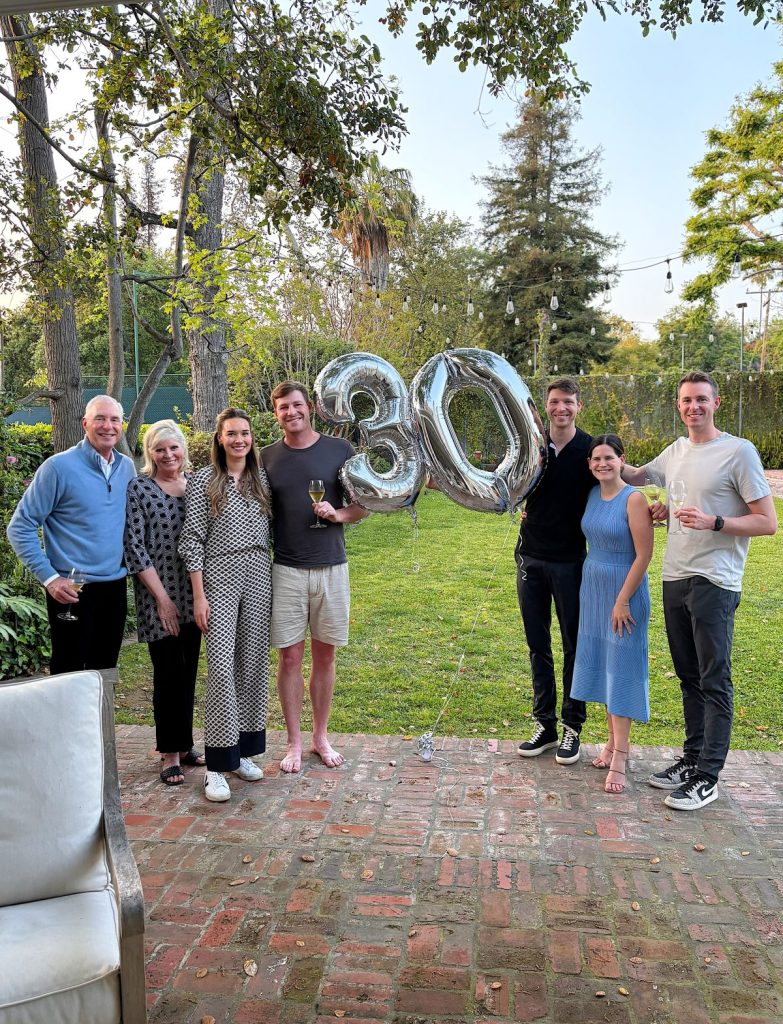 Our family celebrating outdoors, holding shiny "30" balloons in a garden, smiling and posing for a photo.