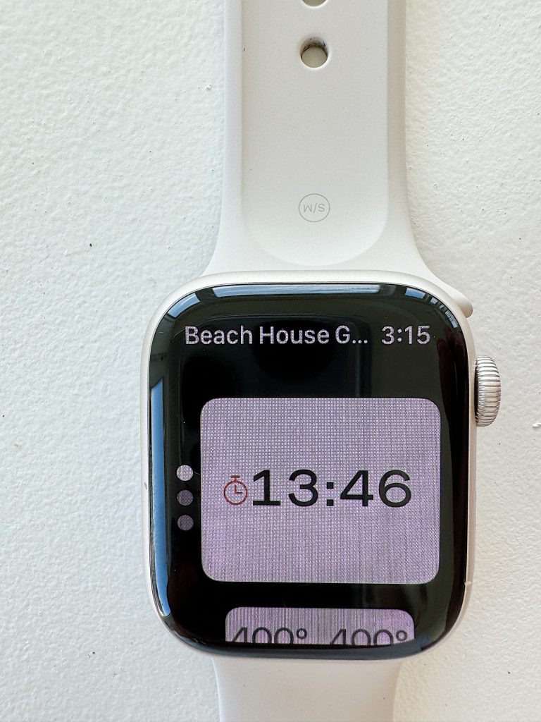 White smartwatch displaying a timer set at 13 minutes and 46 seconds, attached to a cream-colored wall.