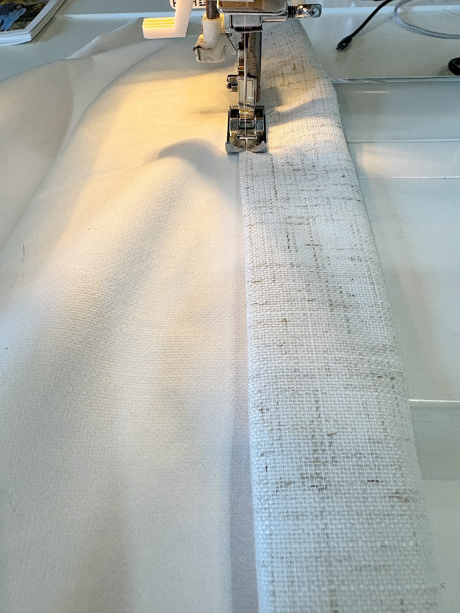 Hemming the drapes above the window seat.