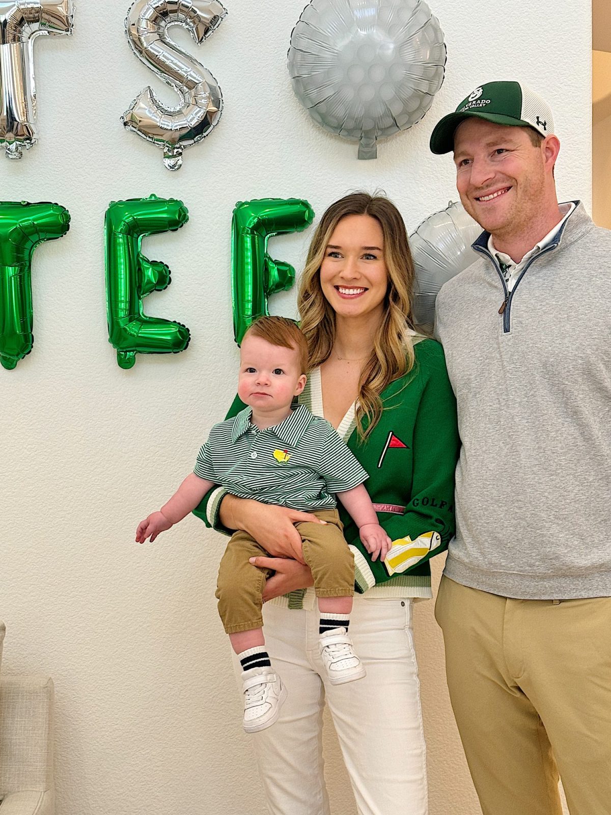 A family posing for a photo with metallic balloons spelling "golf" in the background.