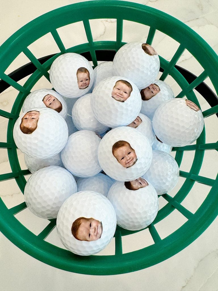 A collection of golf balls with printed faces in a green basket.