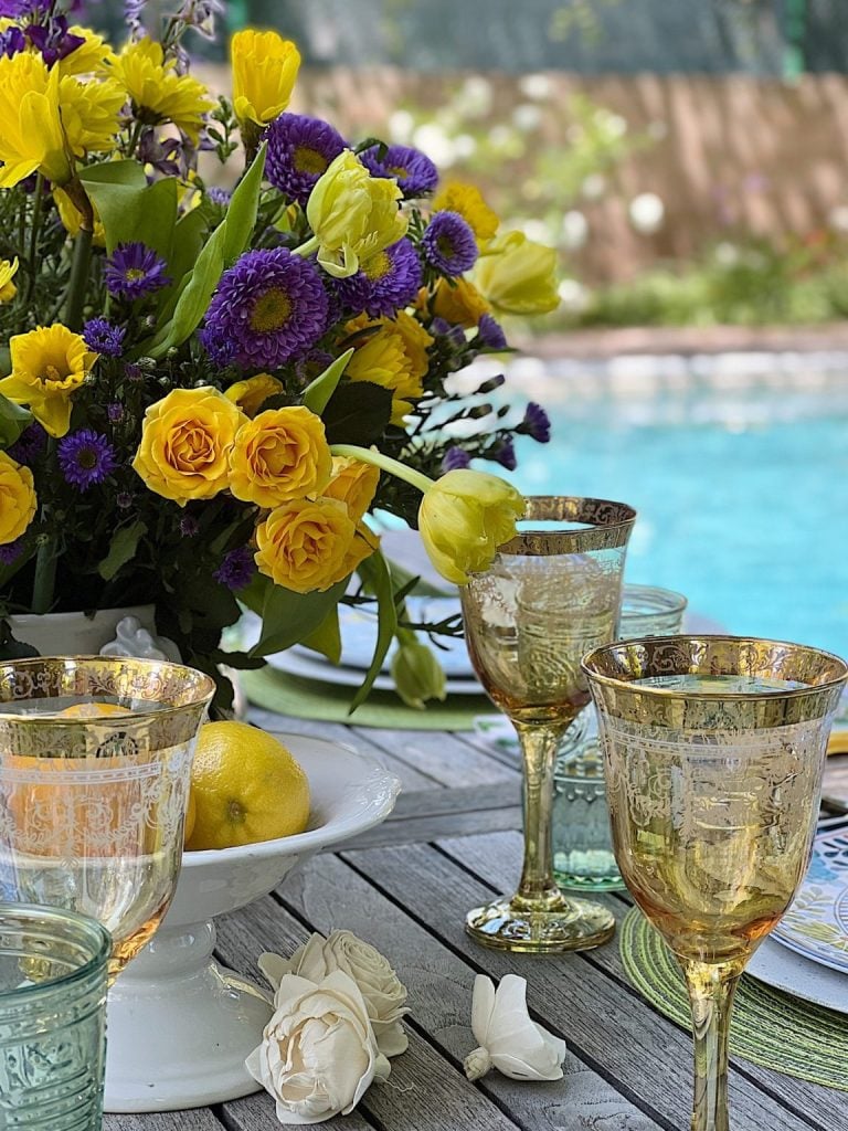 Elegant outdoor table setting for family gatherings, featuring a vibrant bouquet of flowers and ornate glassware with a pool in the background.