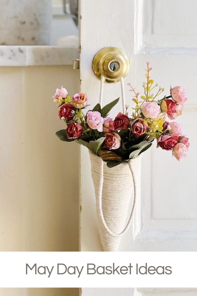 A small hanging basket filled with colorful flowers attached to a white door with a brass knob. text reads "may day basket ideas.