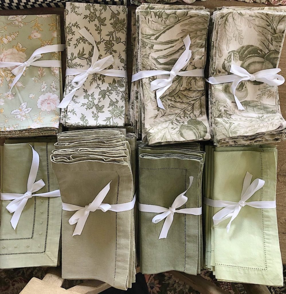 A neatly organized variety of folded linens, each bundle tied with a white ribbon, with the caption "organizing my linen collection.