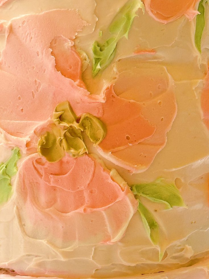 Close-up of a cake with pastel pink and green floral frosting designs.