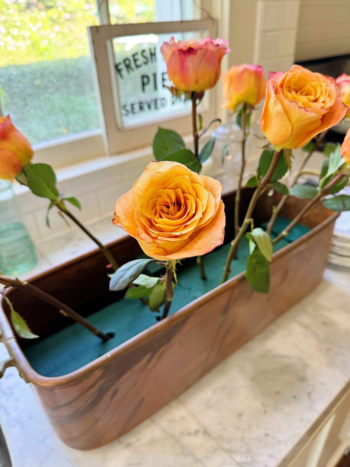 A floral centerpiece, created with sprig colored flowers in a copper vessel.