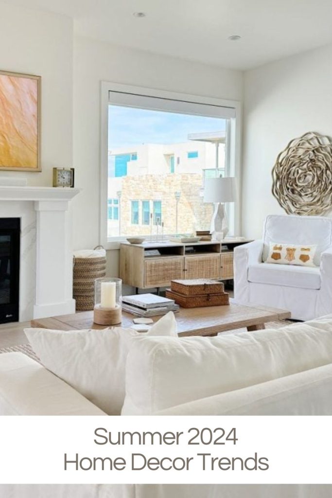 A modern living room with neutral decor, featuring a white armchair, large window, fireplace, wooden coffee table, and wall art. Text at the bottom reads: "Summer 2024 Home Decor Trends.