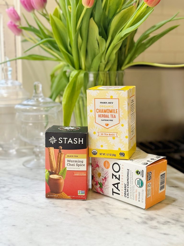 A kitchen counter displaying three boxes of tea: stash warming chai spice, trader joe's chamomile, and tazo chai, with a vase of tulips from Willamette Valley wineries in