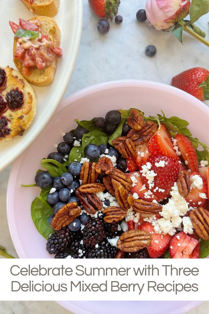 A bowl of salad with mixed berries, pecans, and cheese on a table next to a plate of appetizers. Text below reads, "Celebrate Summer with Three Delicious Mixed Berry Recipes.