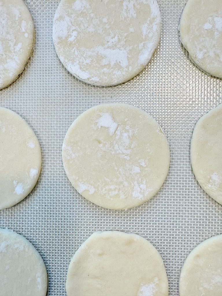Round dough pieces placed evenly on a textured baking sheet, ready for baking.