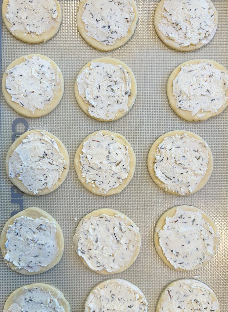 Unbaked round cookies with white, textured dough on a baking sheet, arranged in a grid pattern.