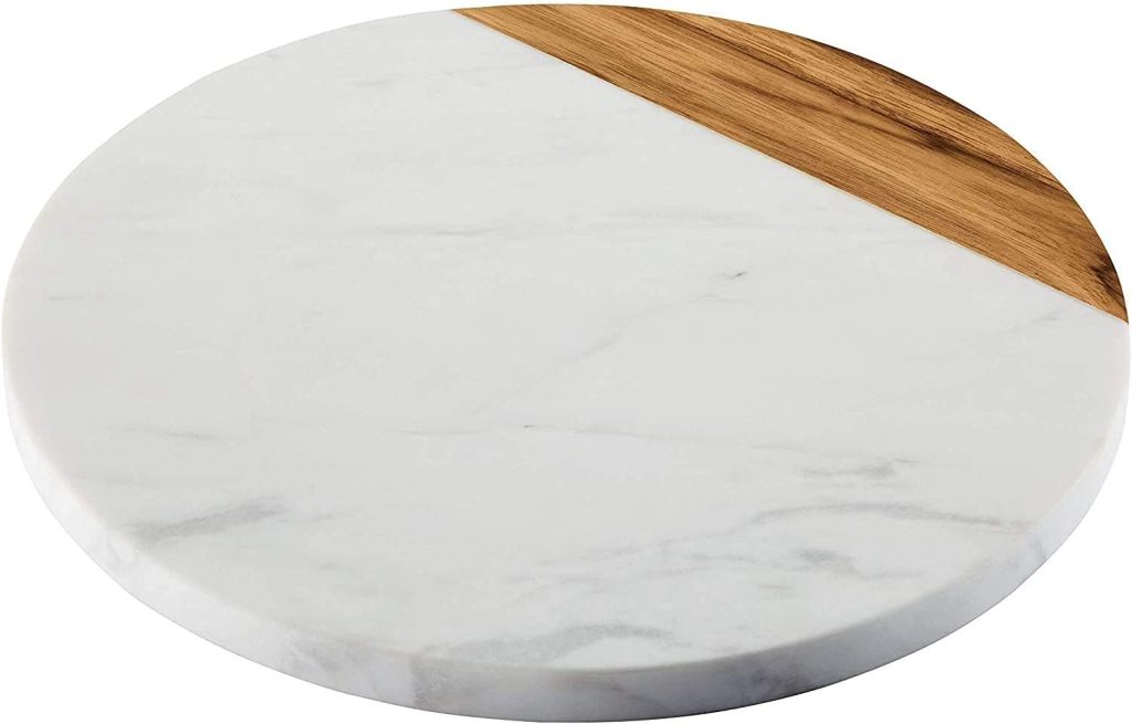 A round serving board with a white marble surface and a small diagonal section of light brown wood—perfect for presenting appetizers alongside your favorite Summer Chicken Recipes.