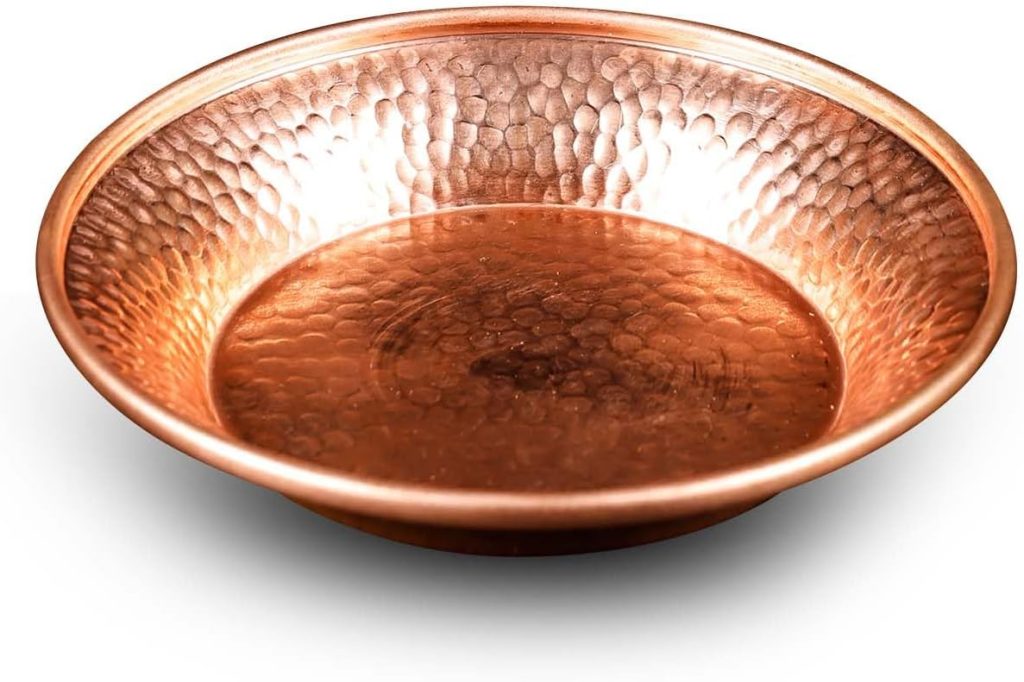 A round, shallow, hammered copper plate with a raised rim evokes the handcrafted texture of paper clay, displayed on a white background.