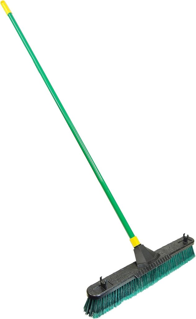 A green-handled push broom with firm, dark bristles and a black plastic base, ideal for maintaining your backyard putting green, shown against a white background.