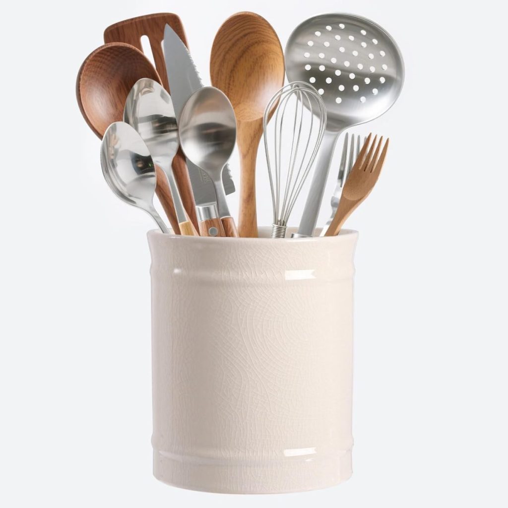 A ceramic container holds assorted kitchen utensils, including wooden spoons, metal spoons, a whisk, spatulas, a slotted spoon, and a fork—perfect for inspiring Creative Crafts in your kitchen.