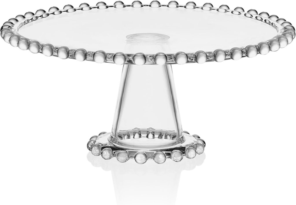 Clear glass cake stand with a round top and bead-like detailing along the rim and base, perfect for showcasing your latest easy cake recipe, set against a white background.