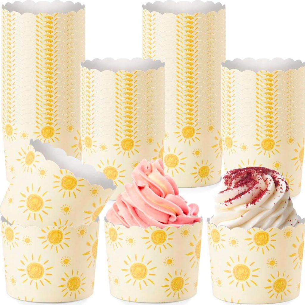 A set of yellow sun-patterned cupcake wrappers, with three cupcakes topped with pink and white swirled frosting, arranged together—perfect for serving treats made from your favorite easy cake recipe.