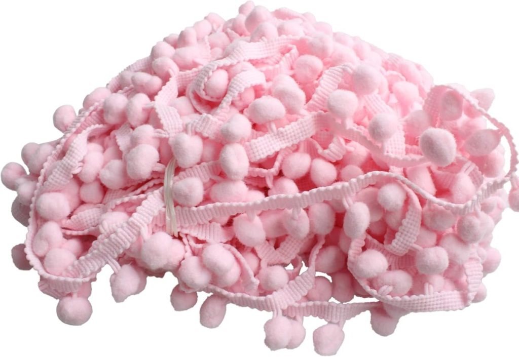 A pile of pink pom pom trim with small soft balls attached to a woven ribbon, perfect for Creative Crafts or sewing decorations.