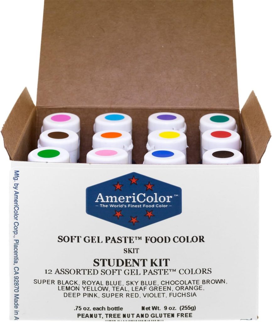 An open box of AmeriColor Soft Gel Paste Student Kit displays 12 bottles of assorted food colors, each with a different colored dot on the lid—perfect for adding vibrant hues to your next easy cake recipe.
