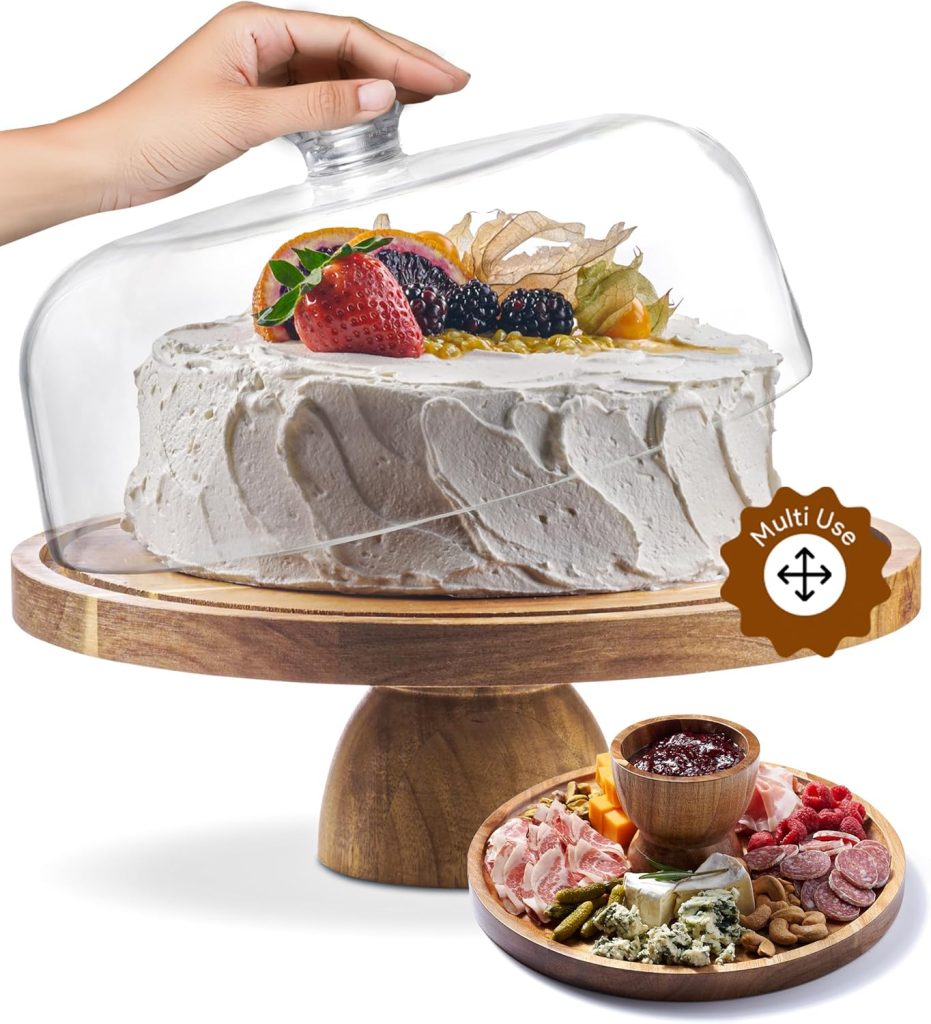 A hand lifts a glass dome from a frosted cake topped with berries on a wooden stand, perfect for showcasing your latest easy cake recipe; the stand also serves as a charcuterie board in an inset image.