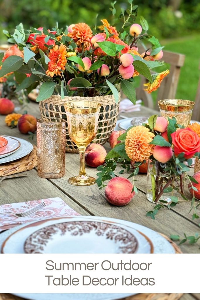 A summer-themed outdoor table with floral arrangements, glassware, and plates, decorated with peaches and vibrant flowers.