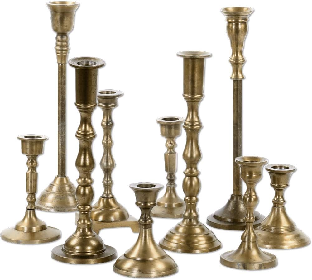 A group of nine vintage brass candlesticks of varying heights and designs, arranged together on a white background—perfect for adding a warm touch to your fall home decor.