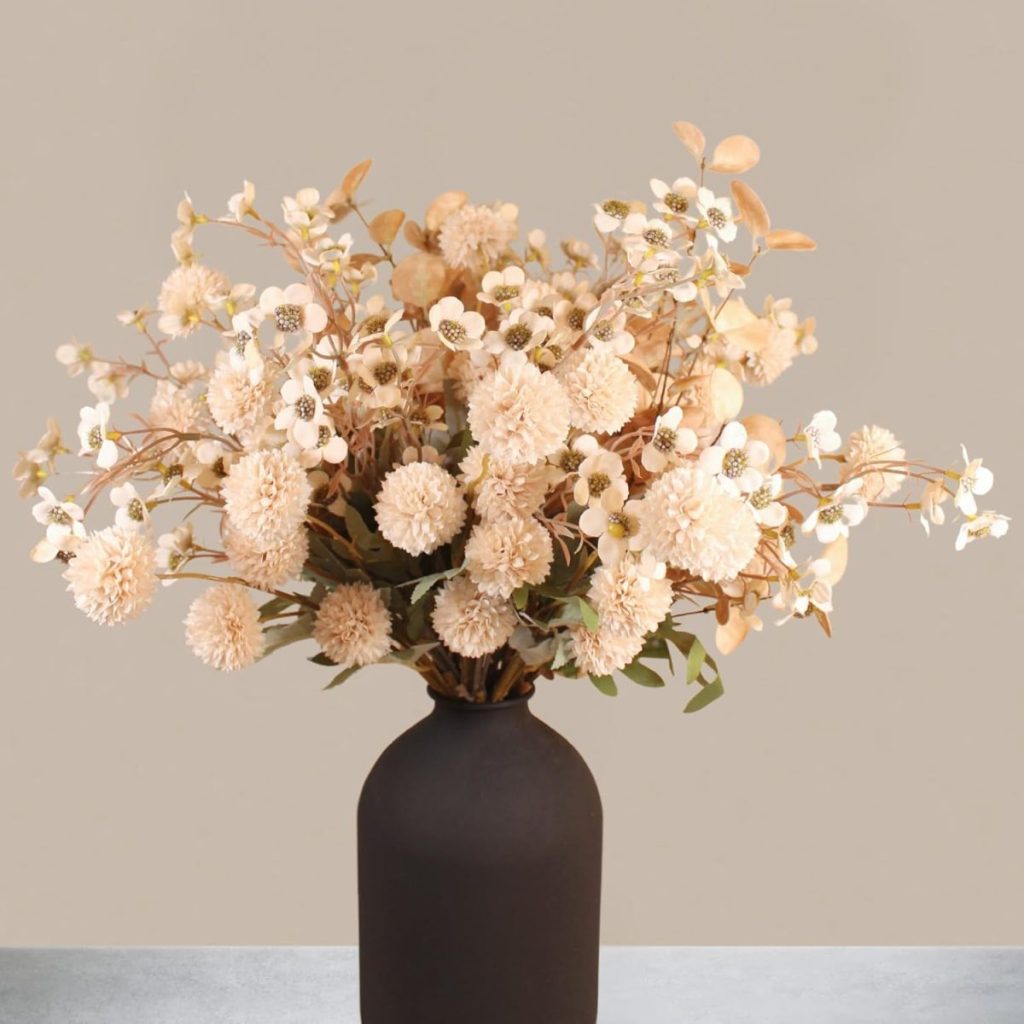 A black vase holding an arrangement of dried beige flowers and foliage, set against a plain light beige background—perfect for adding a touch of fall home decor.